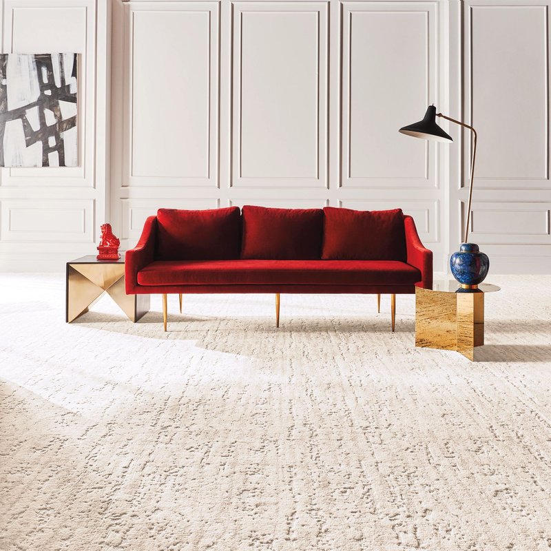 Bright living room with a red velvet couch and beige textured carpet from Triangle Flooring Center in Carrboro, North Carolina